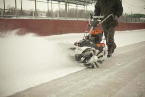 Schneeräumung auf der Eisbahn. Entfernung der Schneeschicht vom Eis. Arbeiter reinigt Stadion von Niederschlag. foto