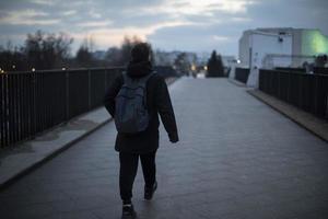 Typ geht abends über die Brücke. Mann nachts in der Stadt. foto