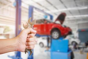 Automechaniker mit Schraubenschlüssel in der Autowerkstatt foto