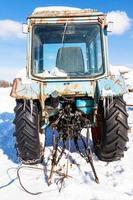 Kaputter Traktor auf verschneiter Straße im sonnigen Wintertag foto