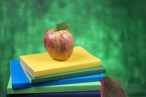 Apfelfrucht auf einem Bücherstapel, auf dem Rücken von Schulklassen. foto