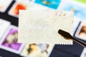 Zange hält Briefmarke mit schlechter Kleberückseite foto