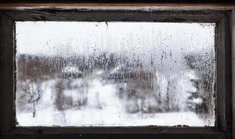 Wassertropfen aus schmelzendem Schnee auf gefrorenem Fenster foto