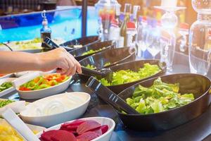 asiatische Frau, die Gemüsezutaten im Salatbar-Restaurant auswählt foto