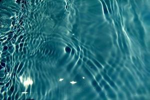 defocus verschwommene, transparente, blaue, klare, ruhige wasseroberflächenstruktur mit spritzern und blasen. trendiger abstrakter naturhintergrund. wasserwelle im sonnenlicht mit kopierraum. blaues aquarell glänzt. foto