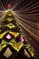 hoher stadtweihnachtsbaum im park mit einer kappe aus lichtergirlanden, leuchtet nachts auf der straße. weihnachten, neujahr, dekoration der stadt. kaluga, russland foto