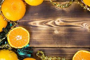 neujahrshintergrund aus holz mit mandarinen, girlandenlichtern und grünem lametta. eine halbe Orange, Zitrusaroma des Urlaubs. weihnachten, neujahr. Platz für Text. rahmen foto