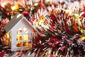 Weißes Holzhaus mit Weihnachtsschmuck, rotem Lametta und goldenen Lichtergirlanden. neujahr, komfort, wärme zu hause, gemütlich. Weihnachtshintergrund. Platz kopieren