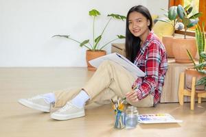 junges Mädchen, das auf dem Boden sitzt und zu Hause auf Papier malt. Hobby und Kunststudium zu Hause. foto
