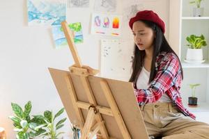 junges mädchen malt zu hause auf papier, holzrahmen, hobby und kunststudium zu hause. foto