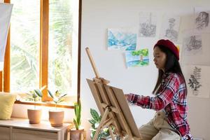 junges mädchen malt zu hause auf papier, holzrahmen, hobby und kunststudium zu hause. foto