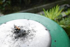 Brennende Zigarette im Aschenbecher auf dem Tisch hautnah foto