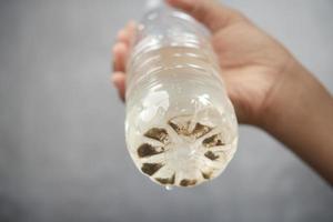 Holding schmutzige Flasche Wasser vor schwarzem Hintergrund foto