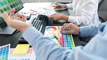 Grafikdesigner-Team, das an Webdesign mit Farbmustern arbeitet und Kunstwerke mit einem Tablet und einem Stift an Schreibtischen im Kreativbüro bearbeitet