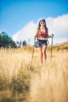 Nordic Walking in den Hügeln, praktiziert von einer schönen jungen brünetten Frau foto