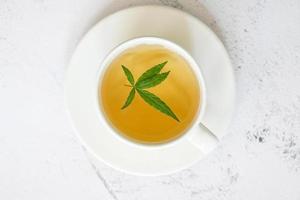 Cannabistee Kräuter auf Teetasse mit Cannabisblatt Marihuanablätter Kraut, Gesundheitstee mit Hanfblattpflanze thc cbd Kräuter Lebensmittel und Medizin foto