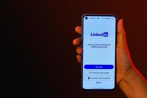 indisches mädchen, das smartphone in der hand hält und linkedin-banner zeigt foto