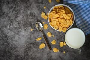 cornflakes schüssel frühstück und snack für ein gesundes lebensmittelkonzept, morgendliches frühstück frisches vollkornmüsli, cornflakes mit milch auf dunklem hintergrund foto