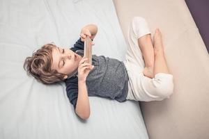 Kind mit Smartphone auf dem Bett. foto