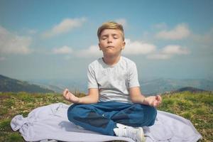 Zen-ähnliches Kind, das Yoga auf einer Wiese praktiziert. foto