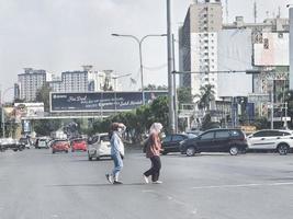 west java, indonesien im juli 2022. zwei muslimische frauen mit kopftüchern überqueren die straße nicht am richtigen ort. foto