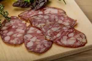 Salami auf Holzbrett und Holzhintergrund foto