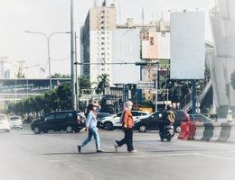 west java, indonesien im juli 2022. zwei muslimische frauen mit kopftüchern überqueren die straße nicht am richtigen ort. foto