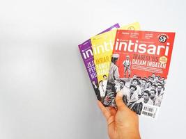 west java, indonesien im juli 2022. eine hand hält einige intisari-magazine foto