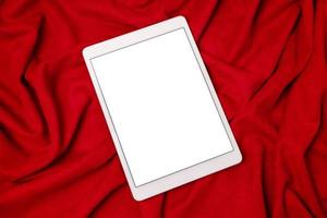 schwarzes mock-up-elektronisches tablet auf rotem stoffhintergrund. Mockup für mobile Apps. leerer bildschirm des smartphones, telefonmodell. foto