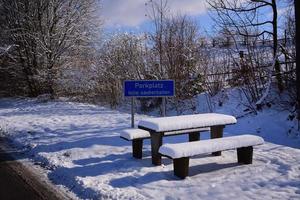 Ein verschneiter Rastplatz am Straßenrand in Deutschland mit Tischen und Bänken im Winter, der menschenleer ist foto