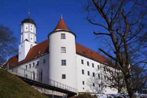 das historische schloss in höchstätt steht auf einem hügel vor blauem himmel, hinter kahlen bäumen, in der sonne foto