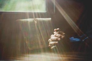 Hand gefaltet im Gebet zu Gott auf heiligem Bibelbuch im Kirchenkonzept für Glauben, Spiritualität und Religion, Frau, die morgens auf heiliger Bibel betet. christlich-katholische frauenhand mit bibelanbetung. foto