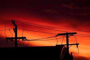 Silhouette von Hochspannungsmast und orangefarbenem blauem Himmelshintergrund am Everning-Tag foto
