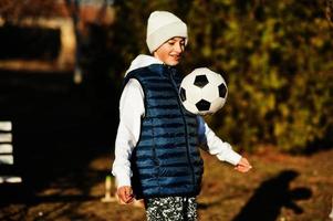 Junge spielt mit dem Fußball im sonnigen Frühlingstag. foto