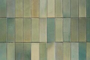 Textur und Muster aus grünen keramischen Wandfliesen, quadratisches Grunge-Mosaik aus nächster Nähe, Hintergrund, Retro-Fassade des Gebäudes. foto