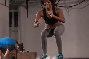 Schwarze Sportlerin führt Boxsprünge im Fitnessstudio durch foto