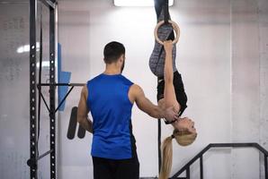 frau, die mit persönlichem trainer an gymnastikringen trainiert foto