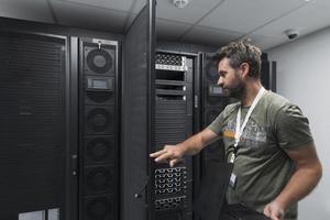 Rechenzentrumsingenieur, der die Tastatur in einer spezialisierten Einrichtung eines Supercomputer-Serverraums mit männlichem Systemadministrator verwendet foto