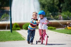 junge und mädchen im park lernen fahrrad zu fahren foto