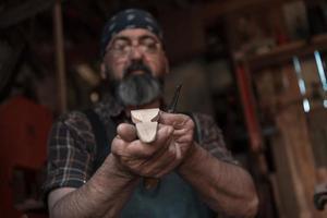 Löffelhandwerksmeister in seiner Werkstatt mit handgefertigten Holzprodukten und Werkzeugen arbeiten foto