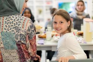 süßes kleines mädchen, das iftar-abendessen mit der familie genießt foto