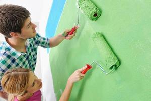 Glückliches Paar malt Wand im neuen Zuhause foto