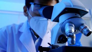 asiatischer wissenschaftler, der recherchiert und im labor durch ein mikroskop schaut. foto