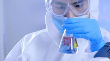 wissenschaftler in der psa-suite, der recherchen durchführt und eine flüssigkeit in einem reagenzglas im labor überprüft. foto