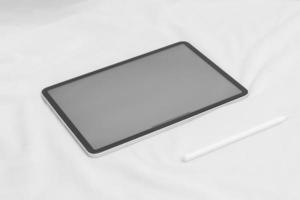 leerer weißer bildschirm der tablette mit bleistift und baumwollblume auf weißem hintergrundmodell für design foto
