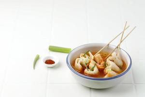Eomukguk- oder Odeng-Suppe, beliebtes koreanisches Straßenessen aus Fischkuchen Eomuk und würziger Gochujang-Paste. auf weißem Tisch foto