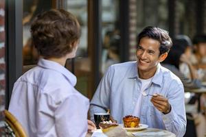 Paar verabredet sich im Café-Bistro im europäischen Stil und genießt die morgendliche Atmosphäre rund um den Stadtplatz mit süßem Gebäck und einer Tasse Kaffee foto