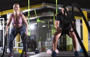 sportpaar, das kampfseile macht, überqueren fitnessübungen foto
