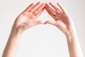 Hände zeigen die Handflächen und spleißen die Fingerspitzen zusammen, um einen Dreiecksrahmen zu bilden. foto