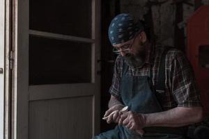 Löffelhandwerksmeister in seiner Werkstatt mit handgefertigten Holzprodukten und Werkzeugen arbeiten foto